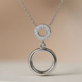Silver necklace with two interlocking rings on a beige background
