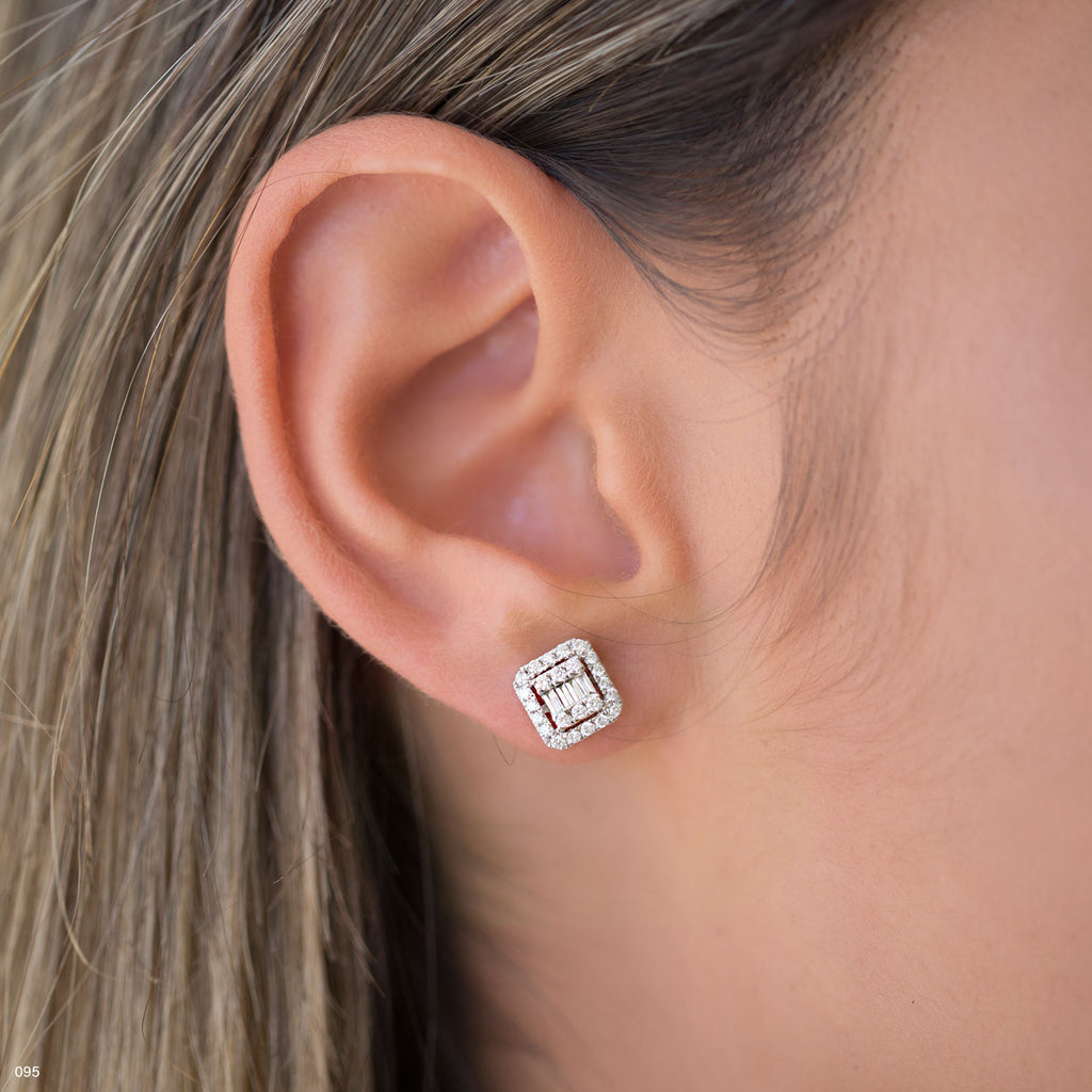 תקריב של אוזן אישה מעוטרת בעגילי סטוד ריבועיים