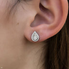 תקריב של אוזן אישה המציגה עגיל טיפה כסף.