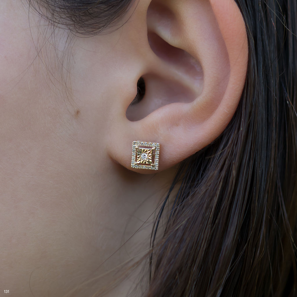 תקריב של אוזן אישה המציגה עגיל סטוד ריבועי.