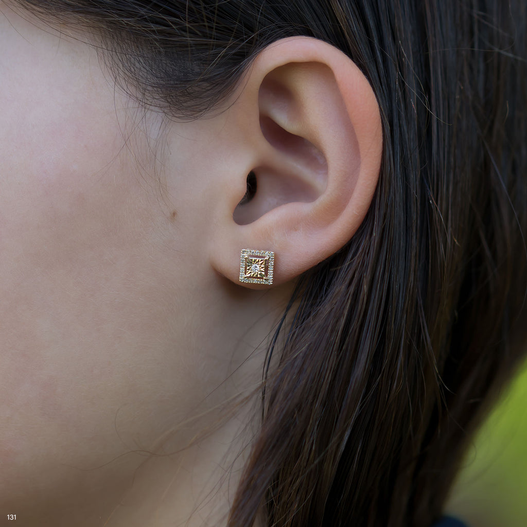 תקריב של אוזן של אדם שעונדת עגיל סטוד בצורת ריבוע.