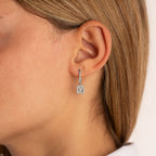 תקריב של אוזן אישה המציגה עגיל מרובע תלוי.