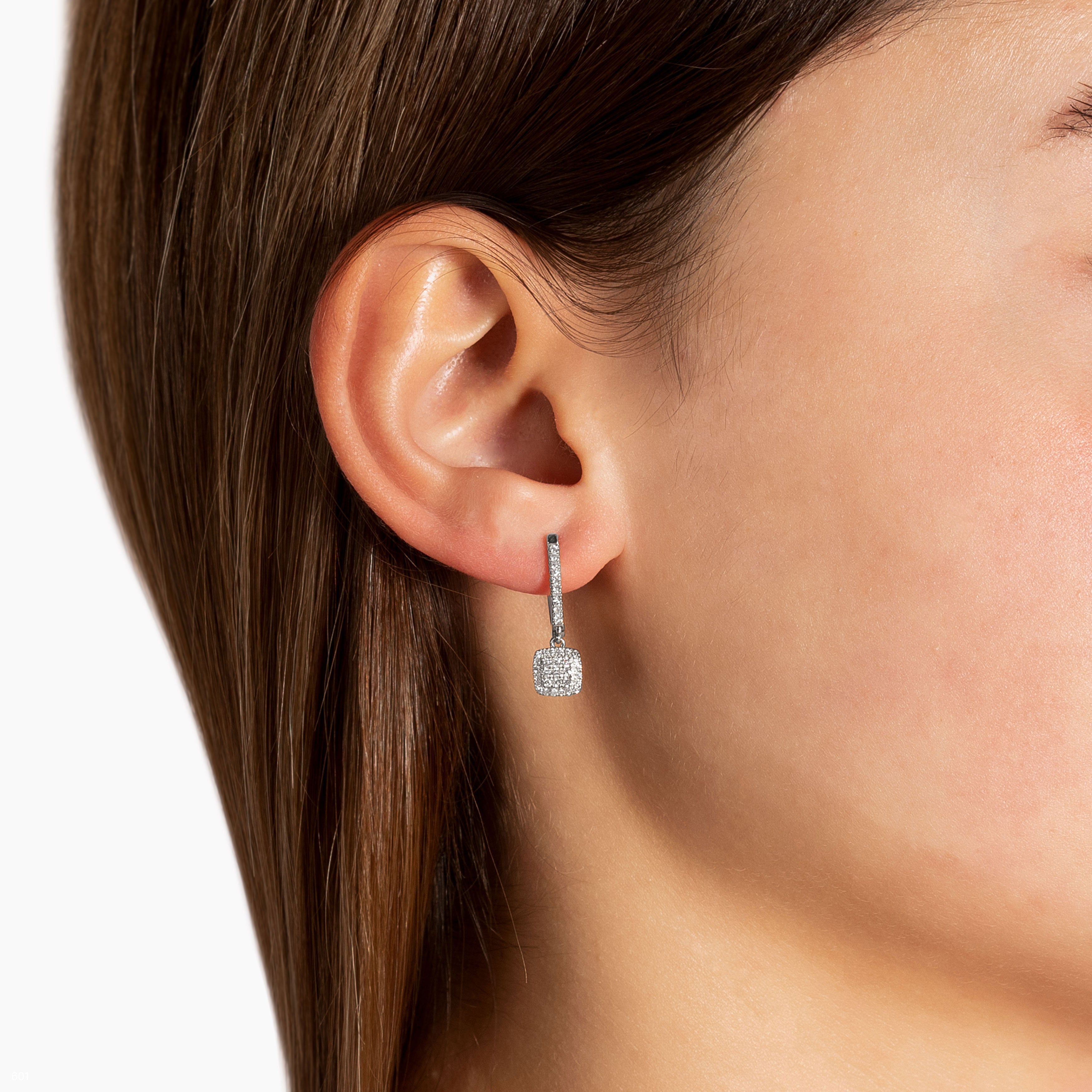 תקריב של אישה שעונדת עגילי יהלומים תלויים.