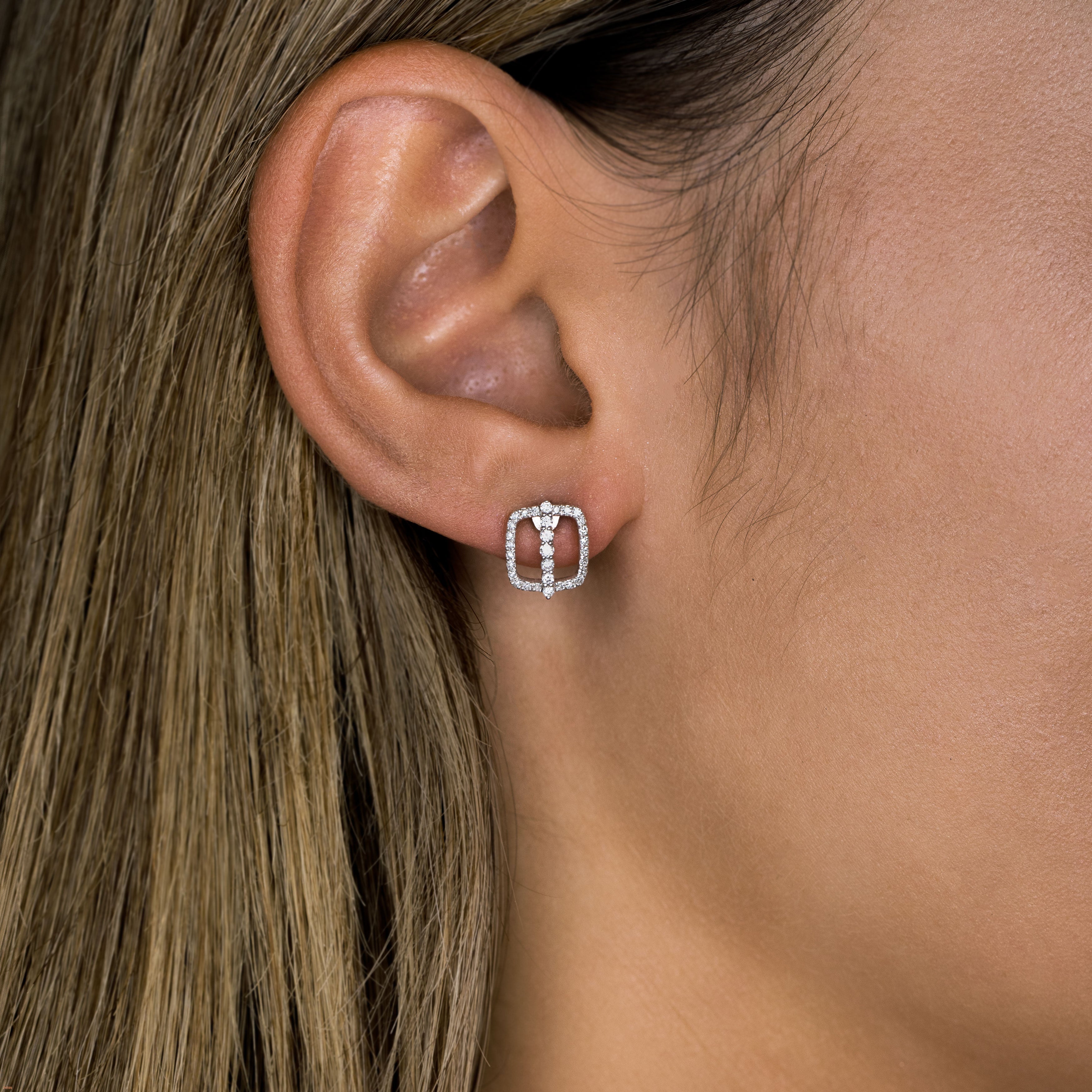 תקריב של אוזן אישה המציגה עגילי יהלומים אלגנטיים.