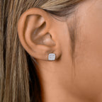 תקריב של אוזן של אדם עם עגיל סטוד בצורת ריבוע.