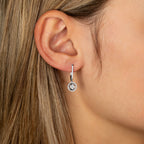 תקריב של אוזן אישה המציגה עגיל תלוי עם אבן עגולה.