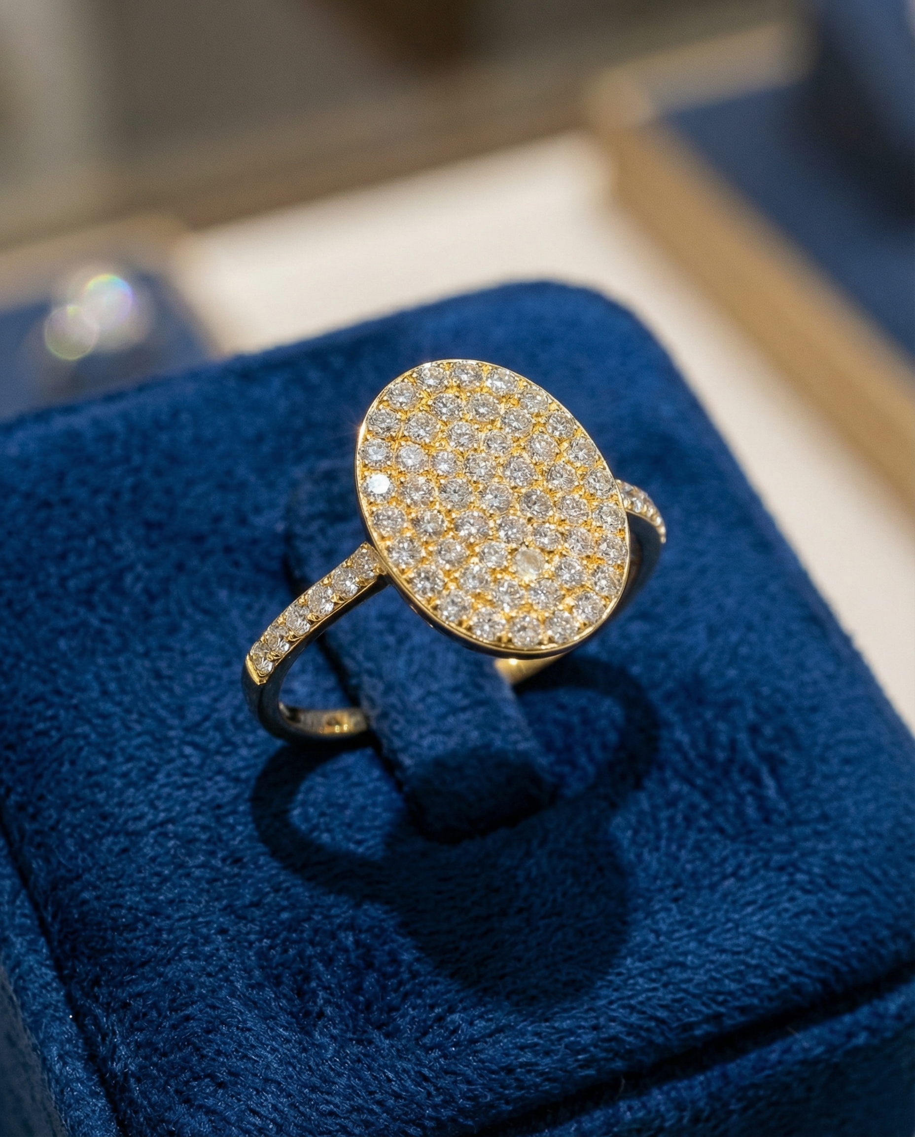 טבעת יהלום מבריקה עם ראש מעוגל ומקושט המוצגת על מעמד קטיפה כחולה.