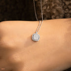 תקריב של שרשרת כסף עם תליונית מרובעת מונחת על פרק כף היד של דוגמנית