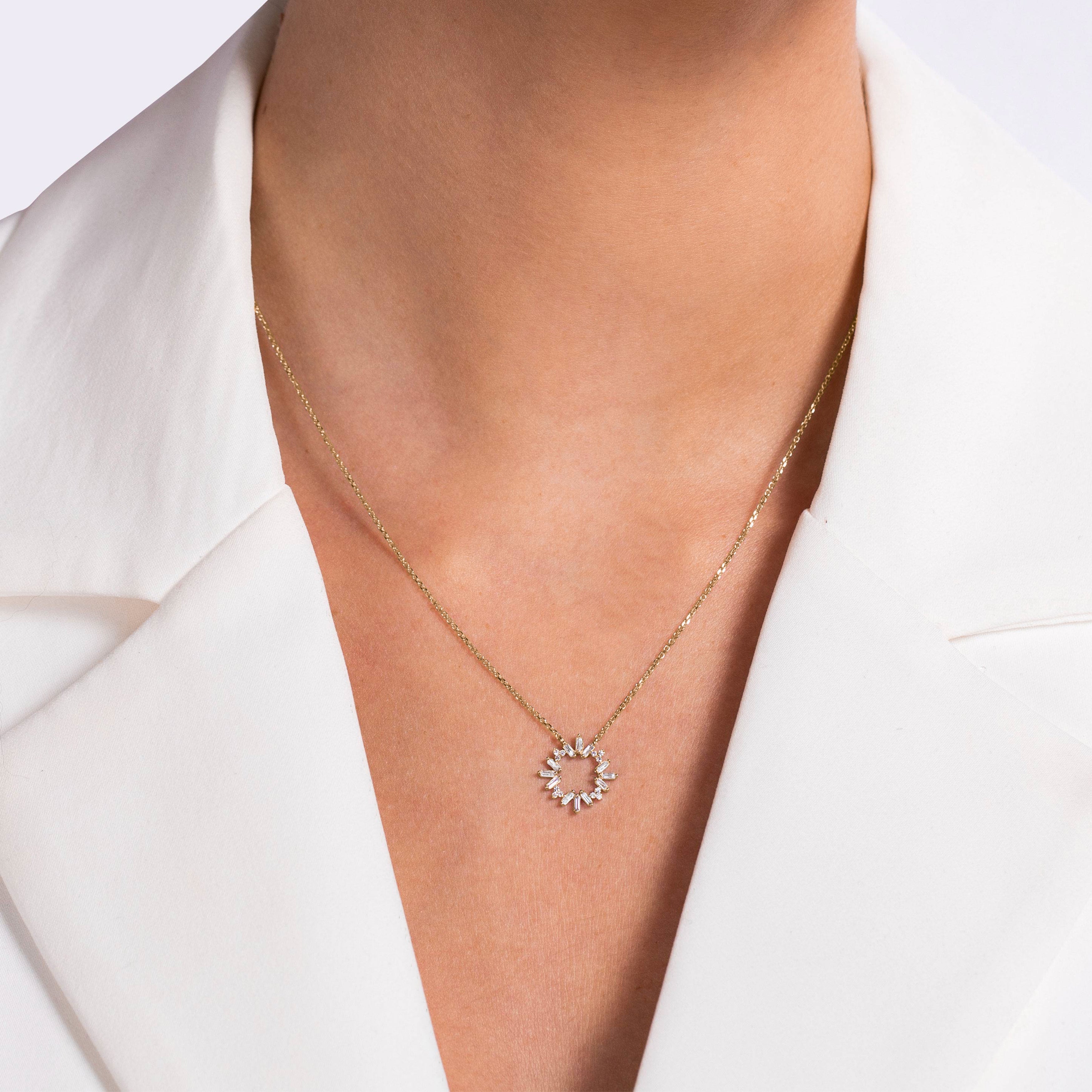 תקריב של שרשרת זהב עם תליוני קשת שמש שנלבשת על ידי אדם בחליפת לבן.