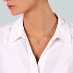 תקריב של אישה לובשת שרשרת כסף עם תליון, לבושה בחולצה לבנה.