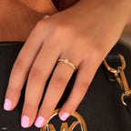 תקריב של יד עם טבעת אופנתית מונחת על תיק יד שחור.