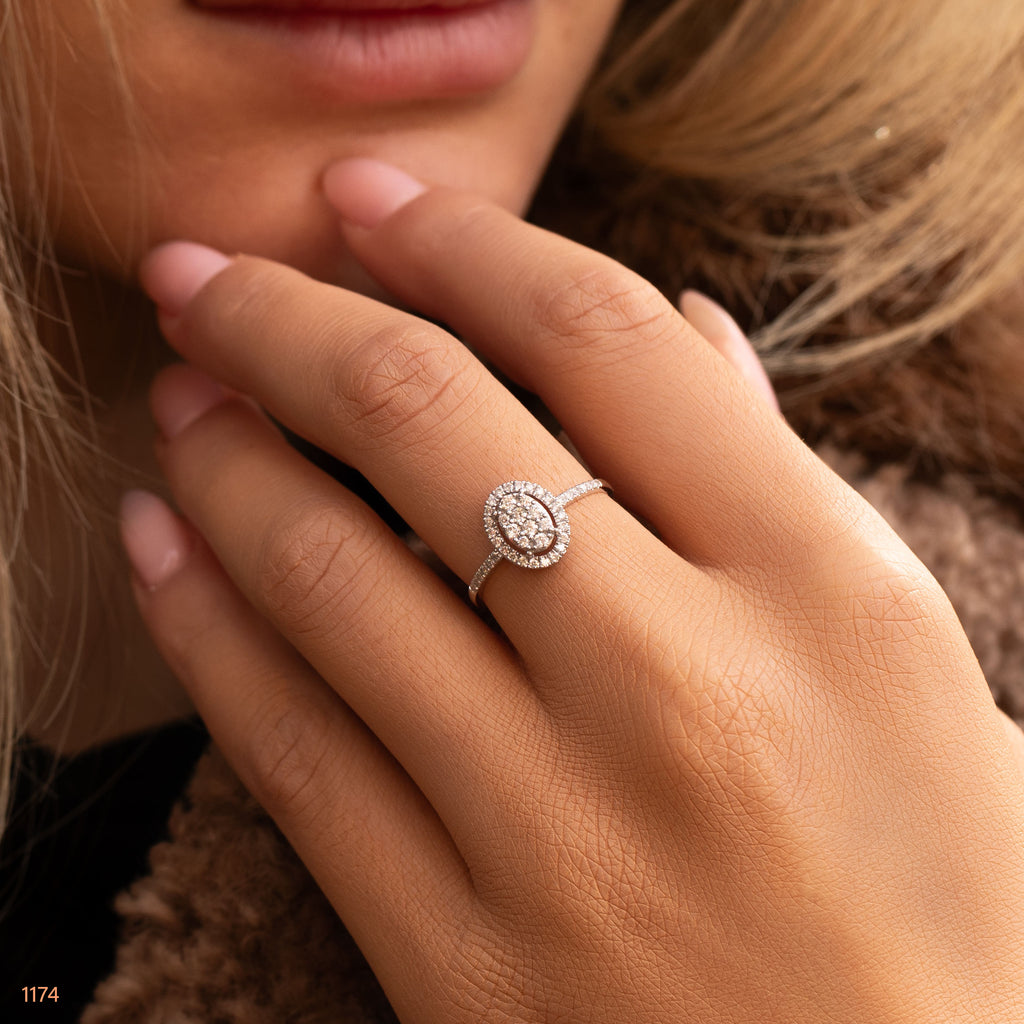 תקריב של יד עונדת טבעת יהלום עם אבן מרכזית אובלית.