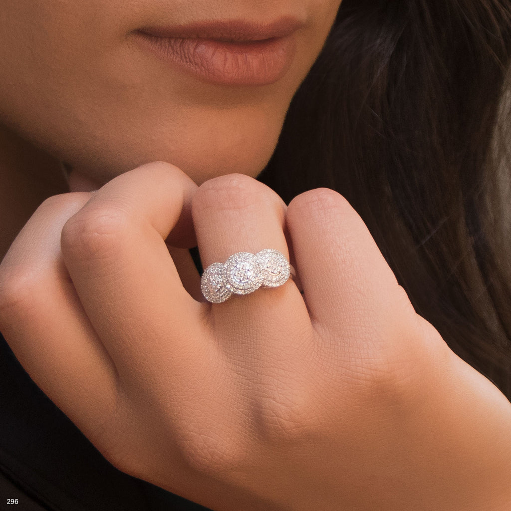 תקריב של יד אישה המראה טבעת שלושה אבנים מבריקות