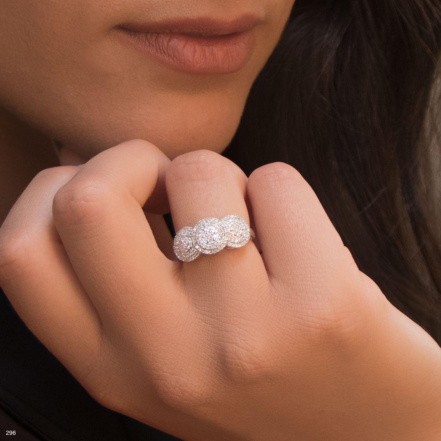 תקריב של יד אישה המראה טבעת שלושה אבנים מבריקות