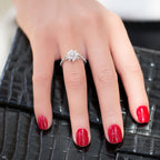 תקריב של יד עם טבעת כסף מבריקה, עם ציפורניים אדומות מוברקות, מונחת על משטח שחור עם מרקם.