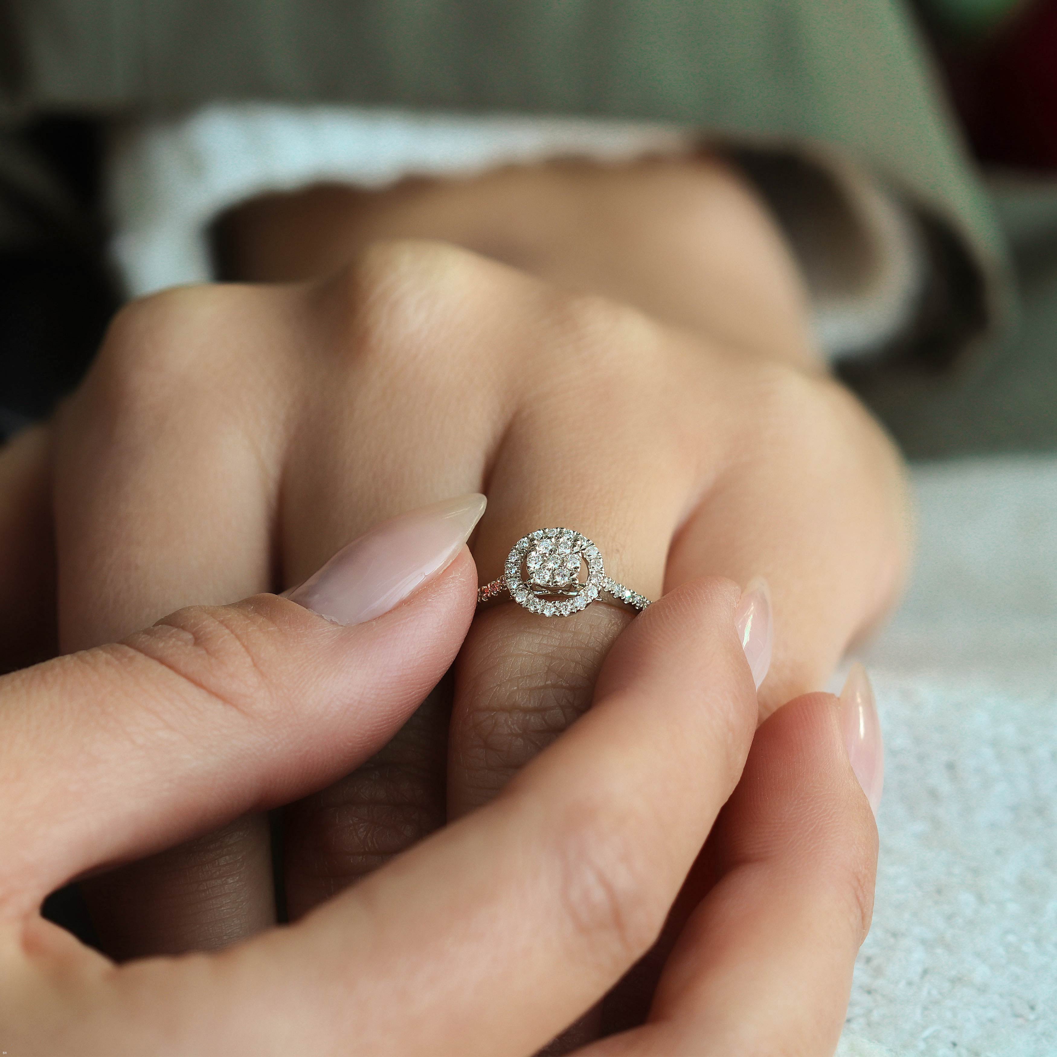 תקריב של יד עונדת טבעת מעוטרת עם עיצוב מעגלי ופרטים מנצנצים.