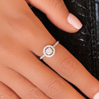 יד עונדת טבעת כסף עדינה עם מרכז יהלום עגול מוקף ביהלומים קטנים יותר.