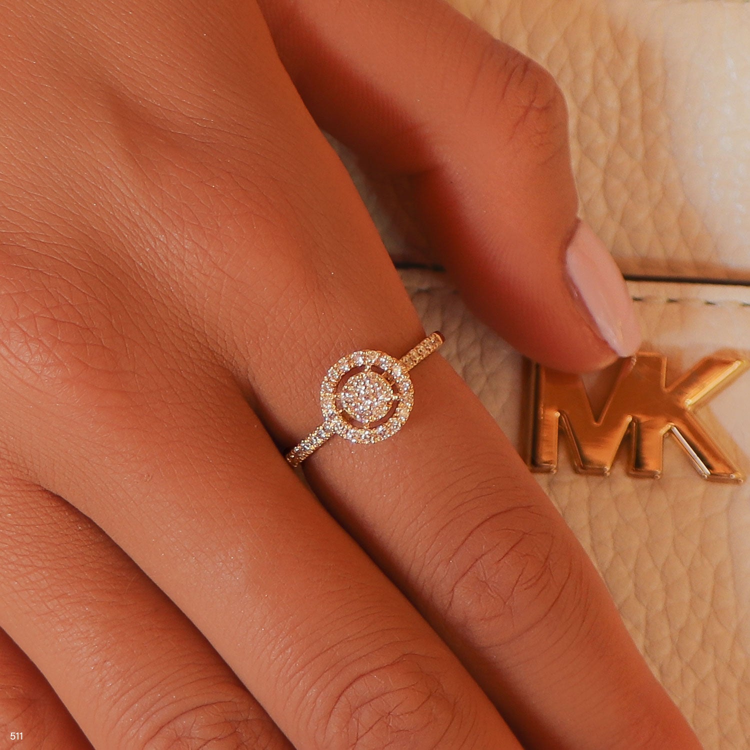 תקריב של יד שעונדת טבעת יהלום ליד תיק אופנה.