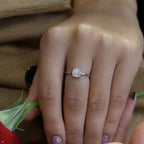 תקריב של יד לובשת טבעת אירוסין מבריקה עם מסגרת פרחונית.