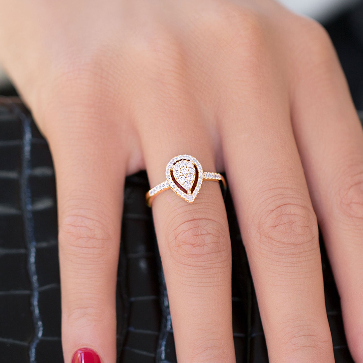 תקריב של יד עונדת טבעת יהלום בצורת אגס.