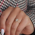 תקריב של יד עונדת טבעת זהב בעיצוב בצורת טיפה עם אבני חן קטנות.