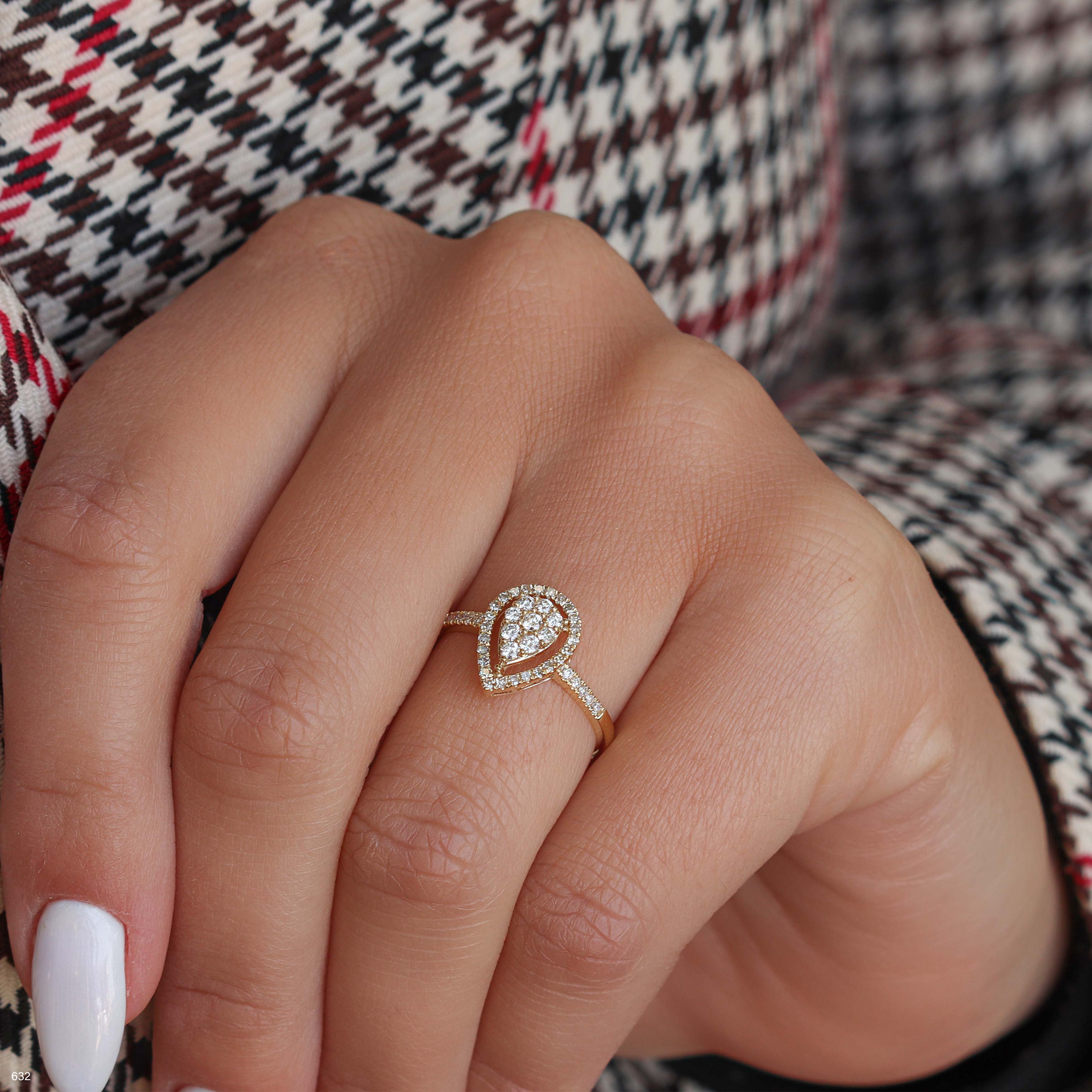 תקריב של יד עונדת טבעת זהב בעיצוב בצורת טיפה עם אבני חן קטנות.