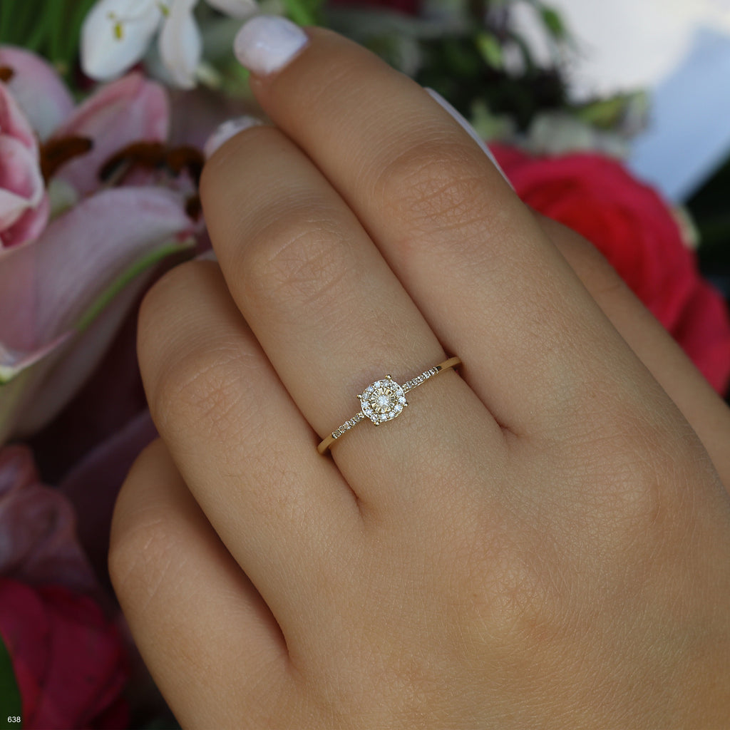 תקריב של יד עונדת טבעת זהב עם יהלום מוקף בפרחים.