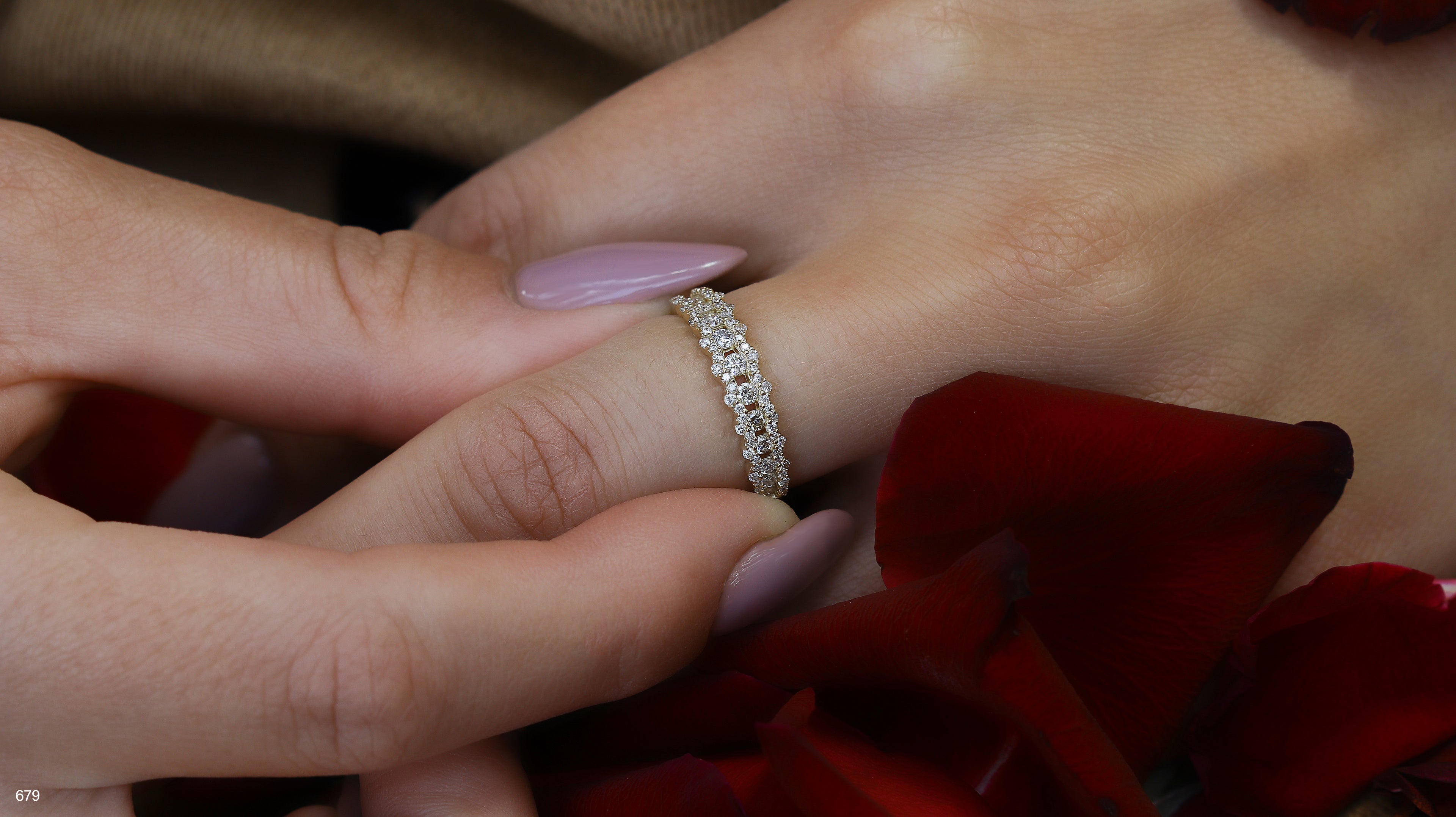 תקריב של שתי ידיים, אחת עונדת טבעת יהלום עדינה, מוקפת בשושנים אדומות.