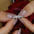 תקריב של אישה מחזיקה טבעת יהלום בין אצבעותיה, עם ורדים אדומים ברקע.