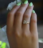 תקריב של יד עם ציפורניים ירוקות בהירות שעונדת טבעת אירוסין עם יהלום מרובע.