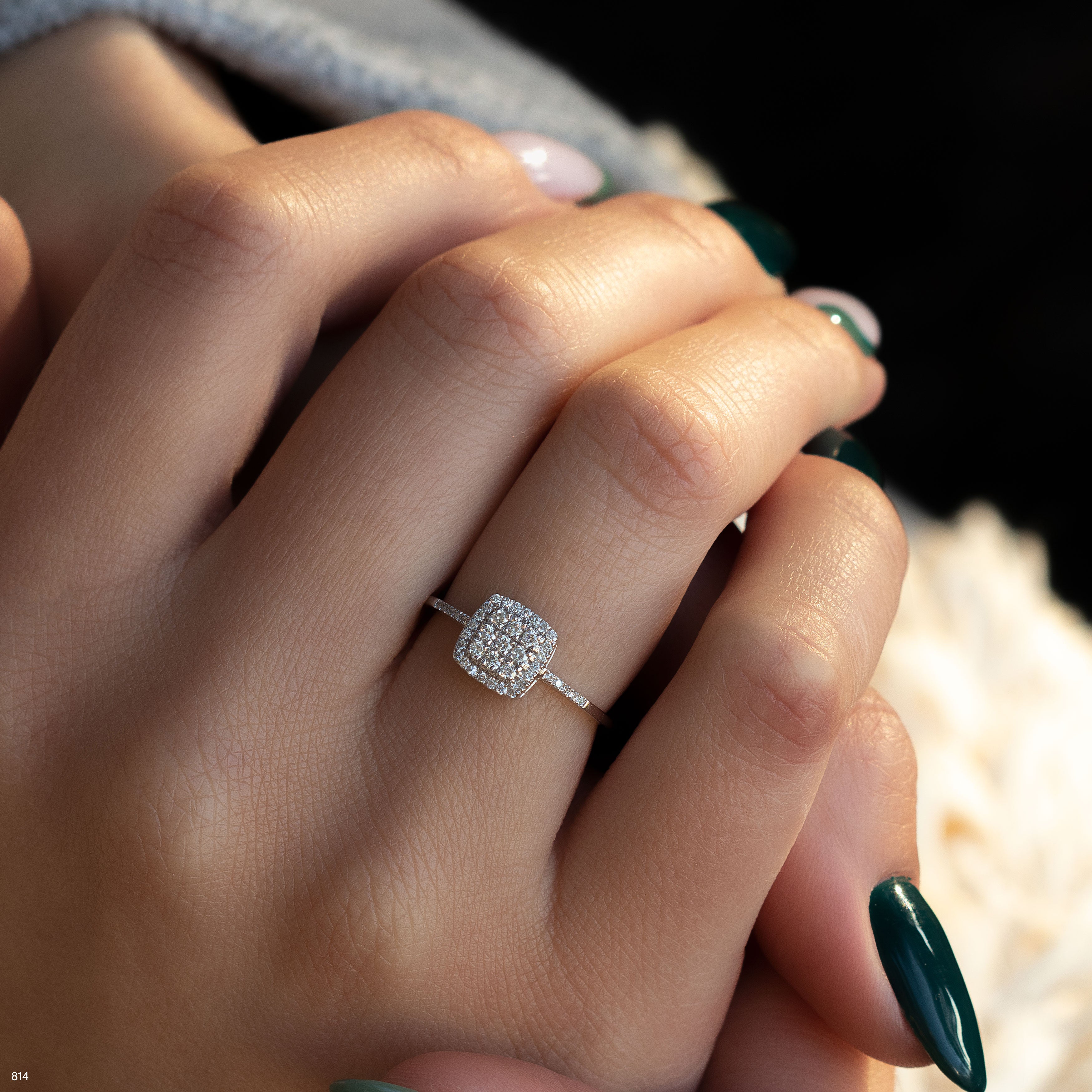 תקריב של יד עונדת טבעת יהלום מבריקה בעיצוב מרובע.