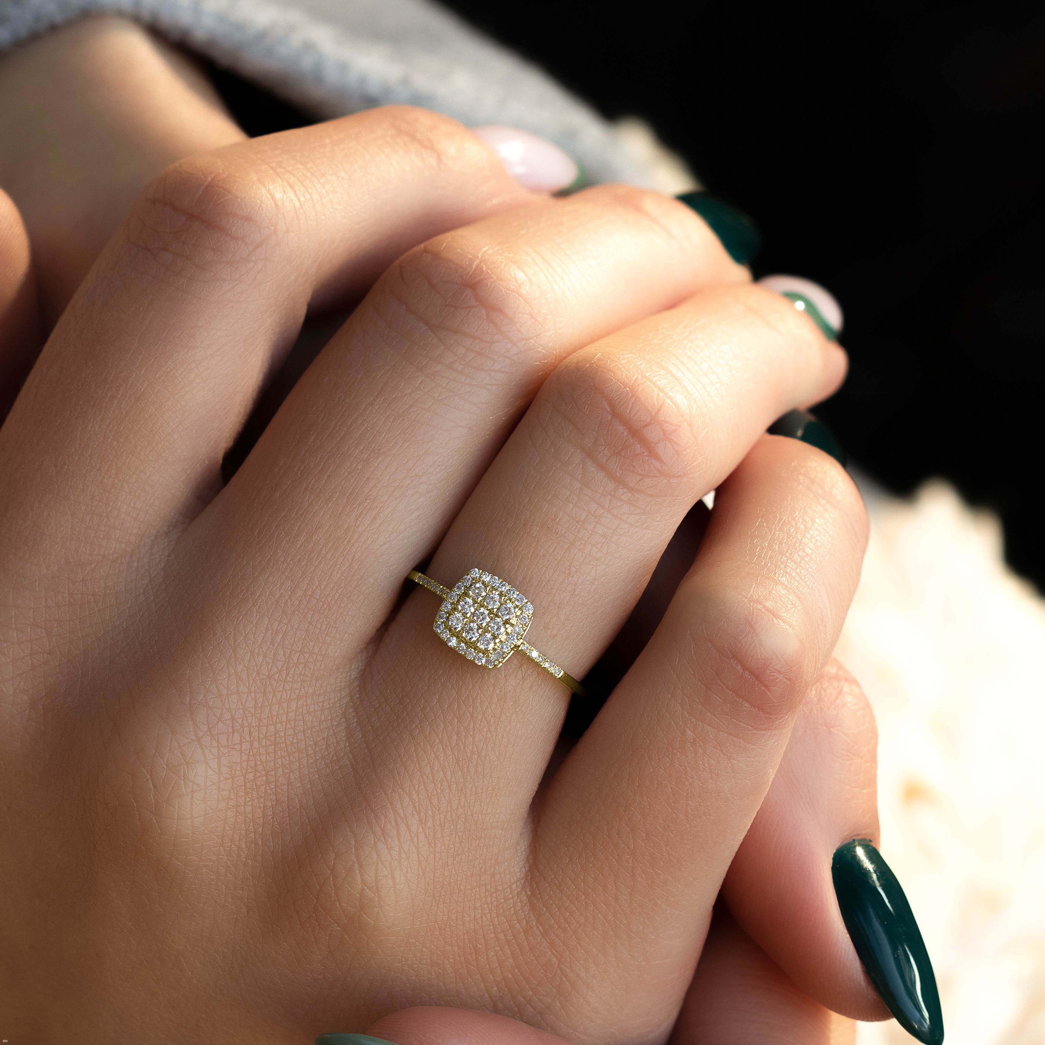 תקריב של יד עונדת טבעת זהב עם מרכז מרובע יהלום.