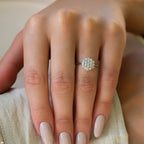 תקריב של יד עונדת טבעת כסף מעוטרת בעיצוב פרחוני ואבני חן קטנות.