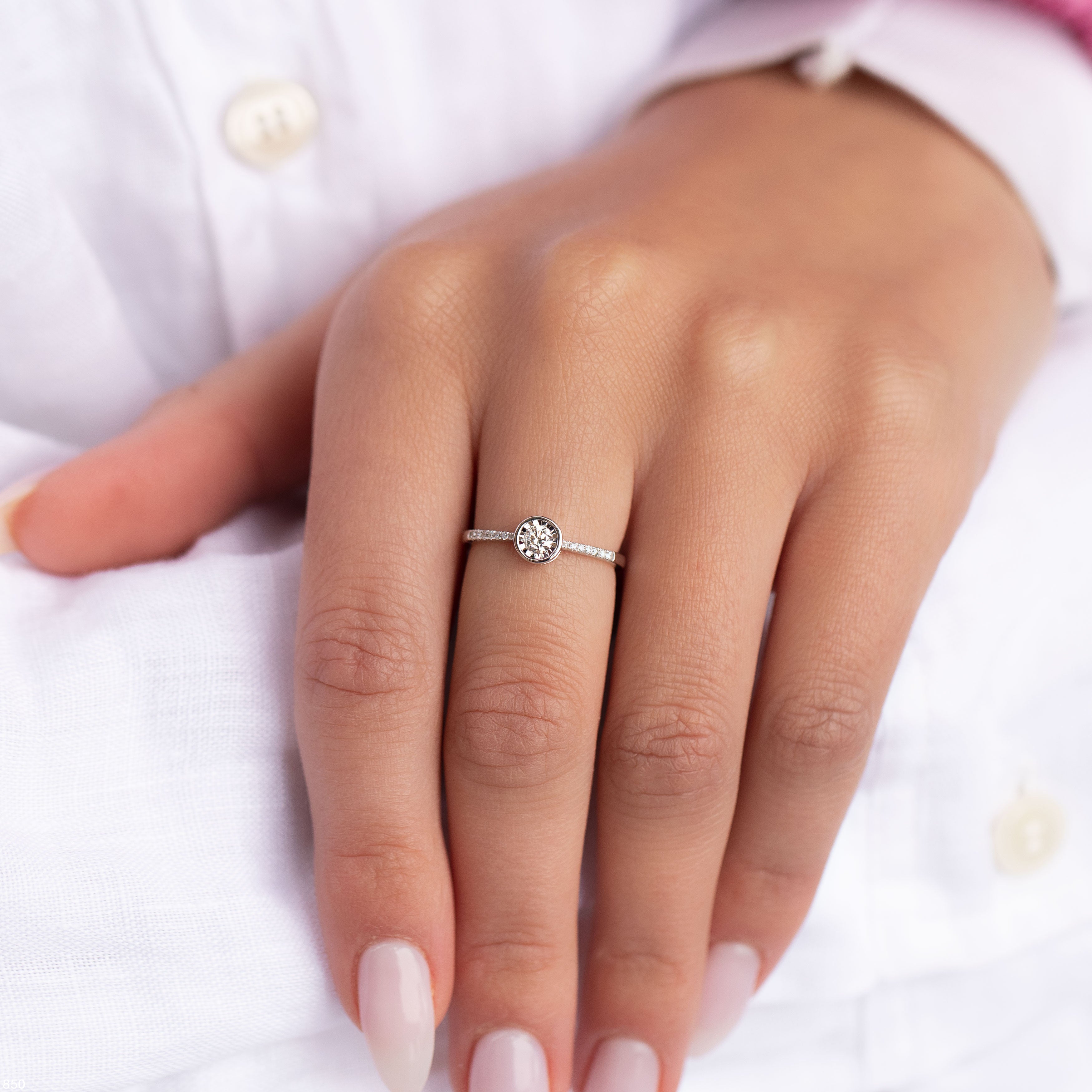 תקריב של יד עונדת טבעת כסף עדינה עם אבן חן עגלגלה.