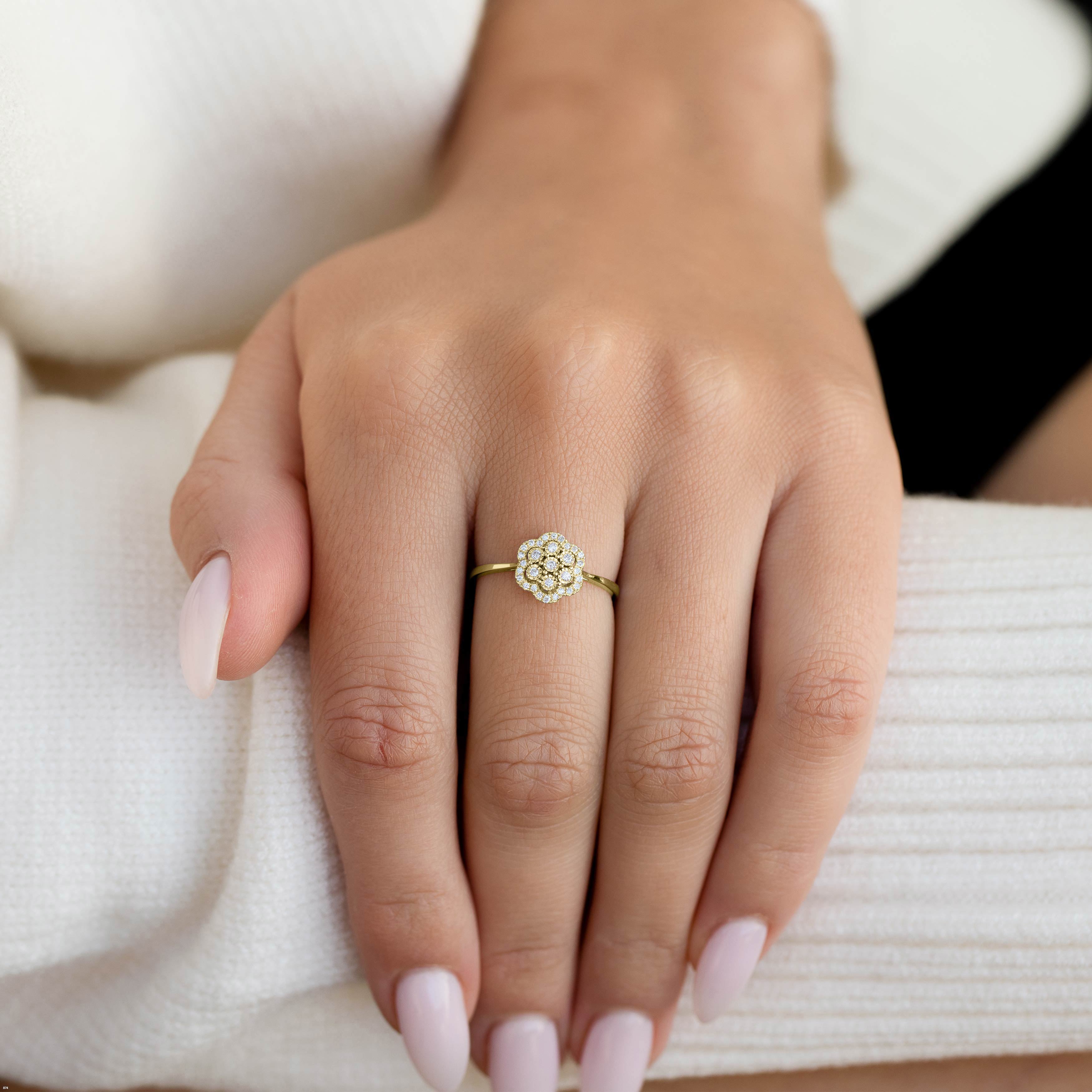 תקריב של יד עונדת טבעת עדינה בצורת פרח עם חישוק זהב.