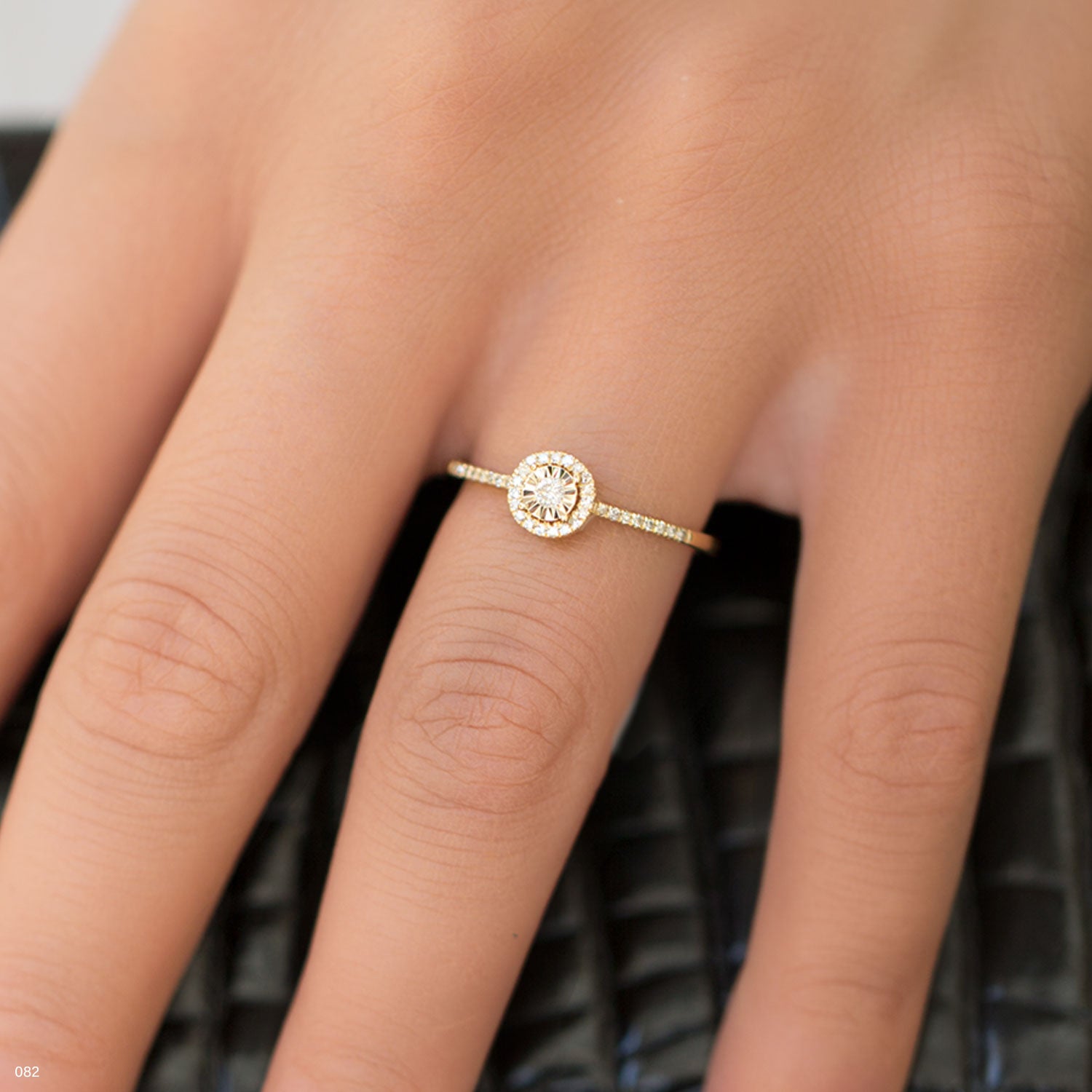 תקריב של טבעת זהב עם אבן חן עגולה על אצבע.