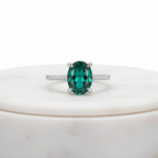 טבעת אבן חן ירוקה אליפטית על משטח שיש