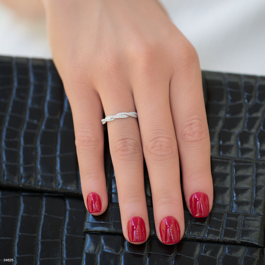 תקריב של יד עם לק אדום שעונדת טבעת כסף, מונחת על משטח שחור עם מרקם.