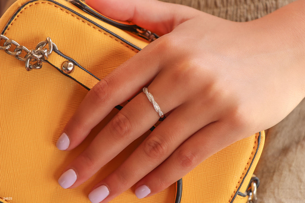 תקריב של יד עם טבעת כסף על תיק יד צהוב.