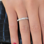 תקריב של יד לובשת טבעת כסף מסולסלת עם אבנים מנצנצות.