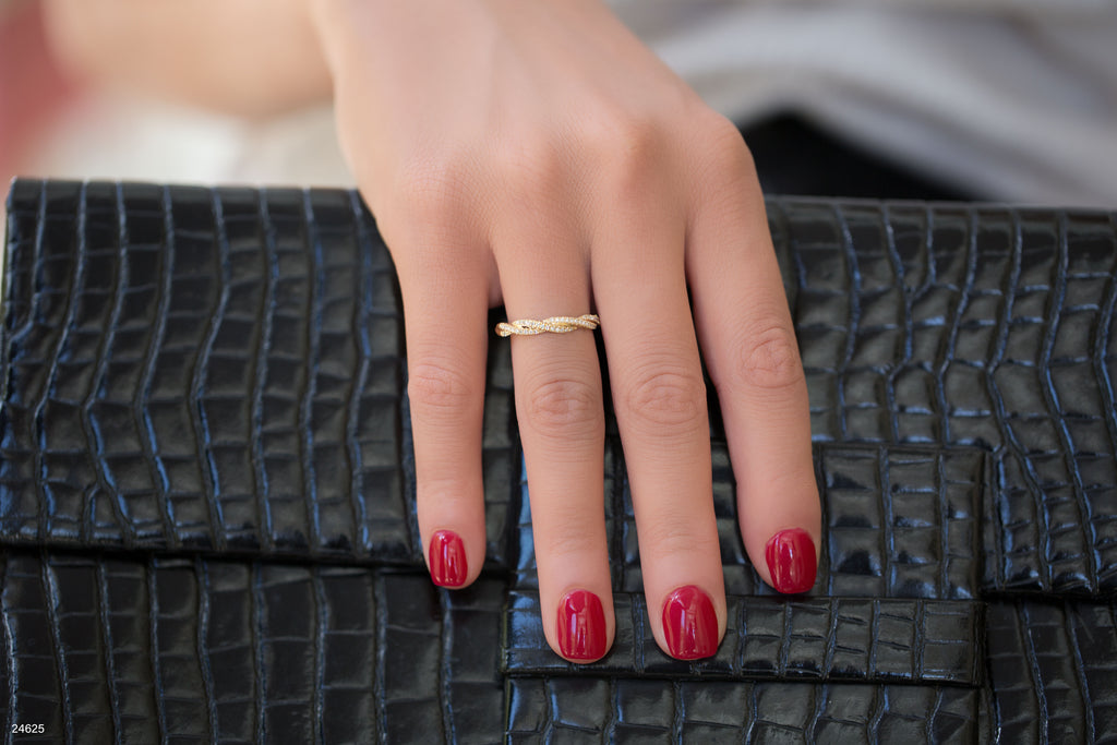 יד עם לק אדום מונחת על תיק יד עם הדפס קрокו שחור.