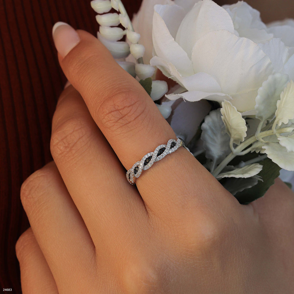 תקריב של יד לובשת טבעת מעוטרת, מחזיקה פרחים לבנים.