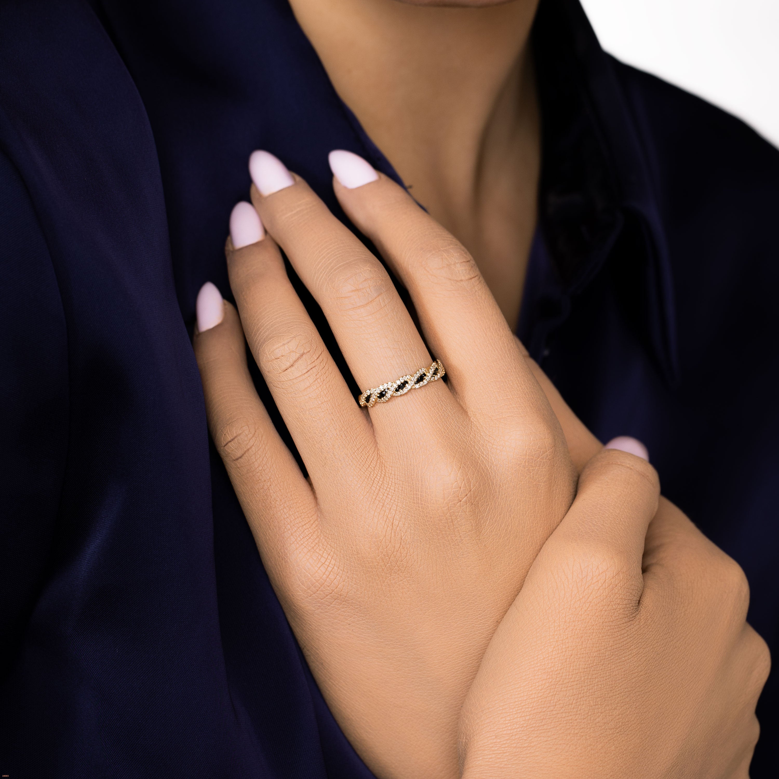 תקריב של יד עם טבעת זהב עדינה, מציגה ציפורניים בגוון ורוד בהיר.