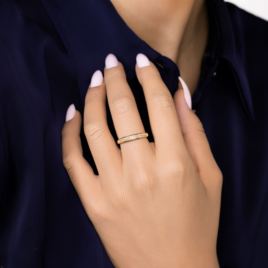 תקריב של יד עם טבעת זהב, מונחת על חולצה כחולה כהה.