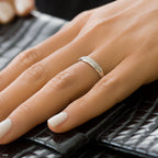 תקריב של יד עונדת טבעת כסף עם אבנים דקורטיביות, מונחת על משטח שחור עם מרקם.