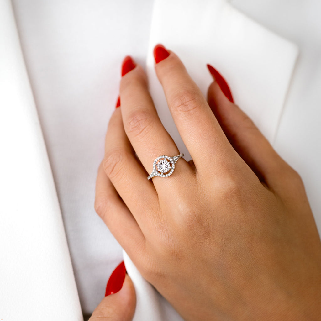 תקריב של יד עונדת טבעת כסף עם עיצוב מעגלי ואבנים מנצנצות.