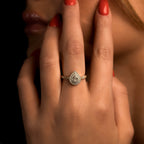 תקריב של יד עם טבעת יהלום בצורת אגס, לק בצבע אדום.