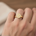 יד לובשת טבעת זהב עם עיצוב אובלי דקורטיבי והדגשות מנצנצות.